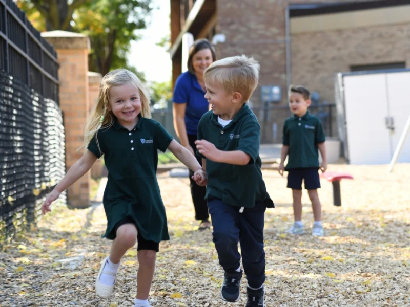two preschool students running on playground